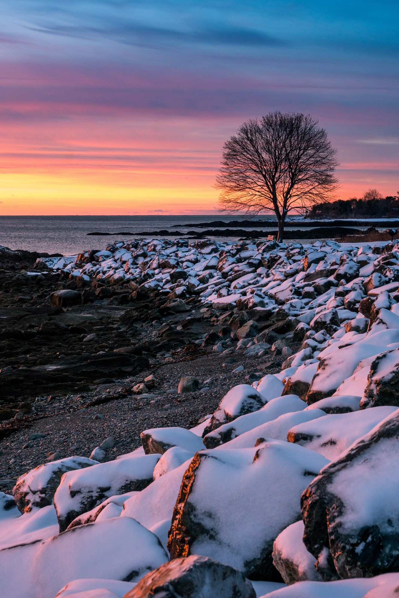 snowy rocks durings a winter sunrise in the great island commons in new castle new hampshire | photo by jake landon schwartz