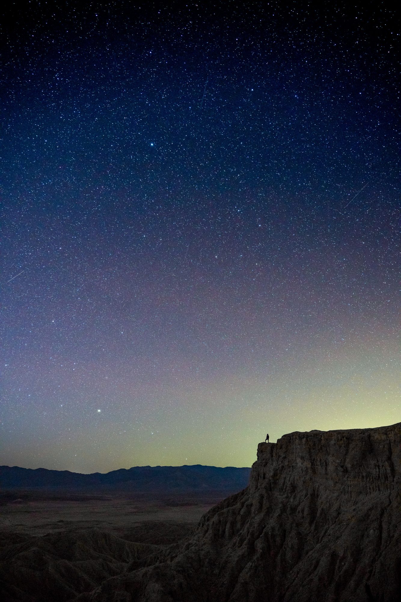 astrophotography long exposure of lizz quass on a ledge at fonts point in anza borrego state park under a starry sky | photo by jake landon schwartz