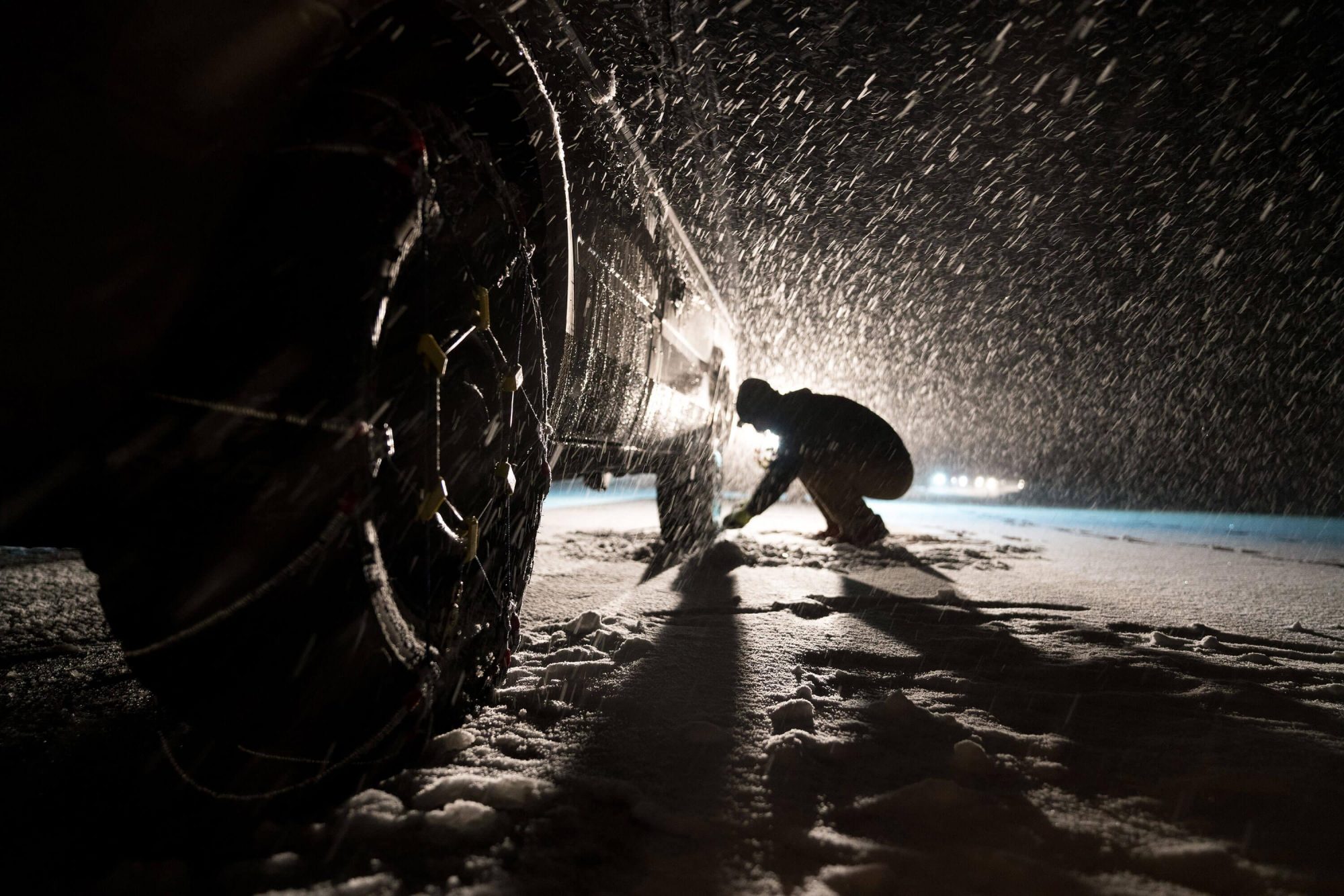 gennaro ameno puts chains on his gray mercedes sprinter van in a snow storm in tahoe california | photo by jake landon schwartz