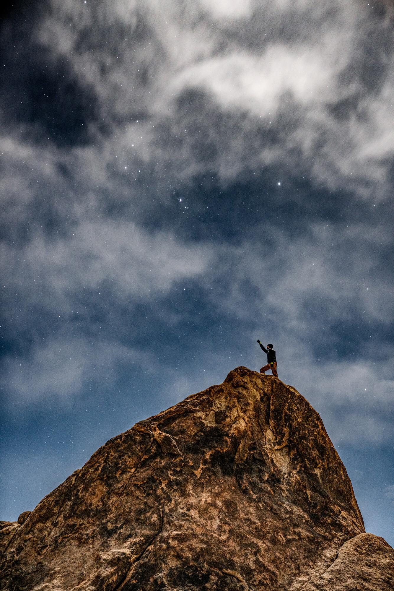 long exposure of man standing on top of a rock under a cloudy and starry sky in alabama hills california | photo by jake landon schwartz