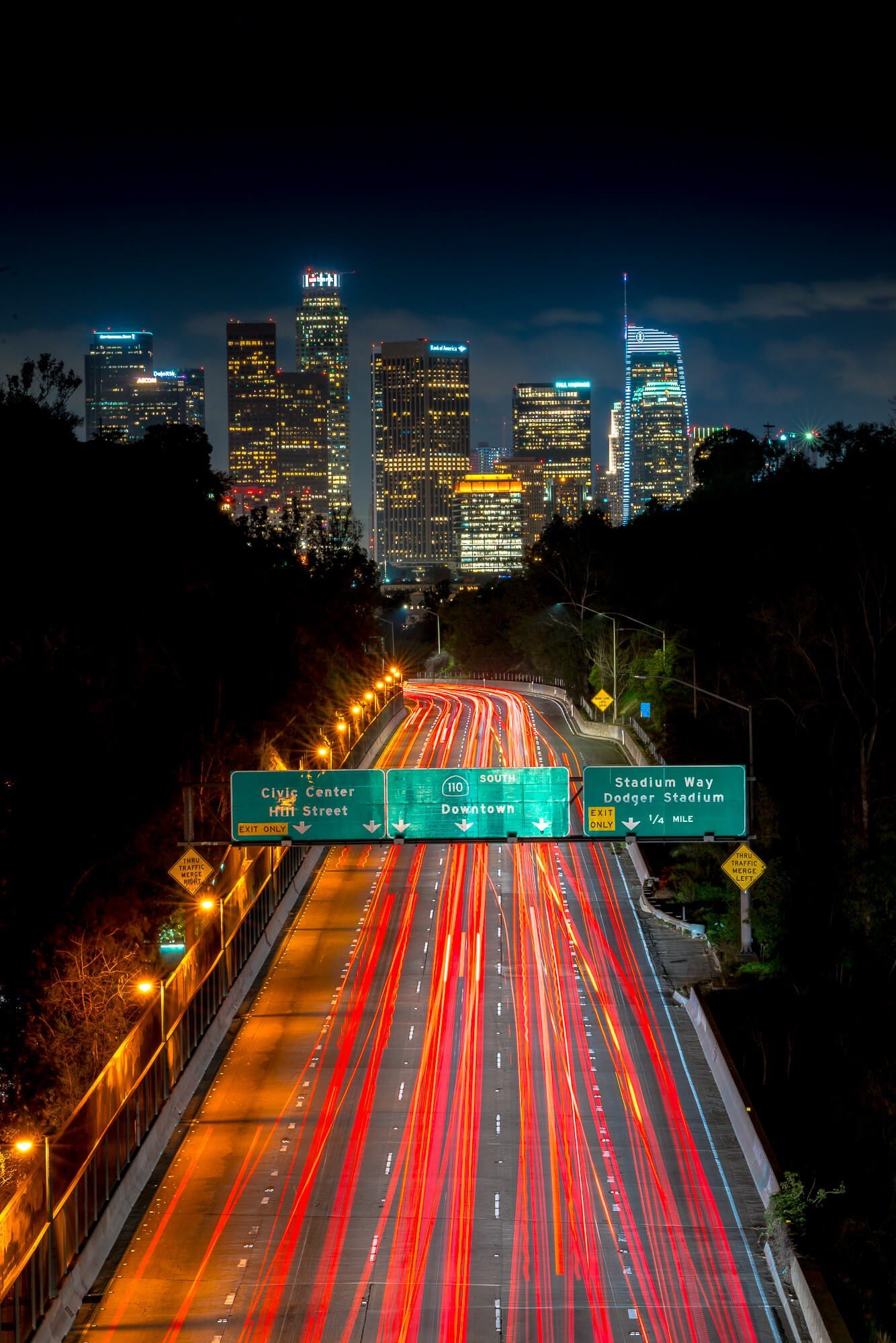 long exposure of traffic with downtown la los angeles behind it during night as seen from elysian park | photo by jake landon schwartz