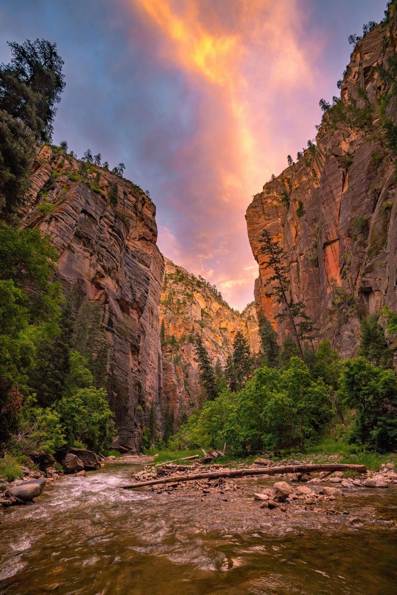 a dramatic sky of pink clouds as seen from inside the virgin narrows during sunset at zion national park in utah | photo by jake landon schwartz