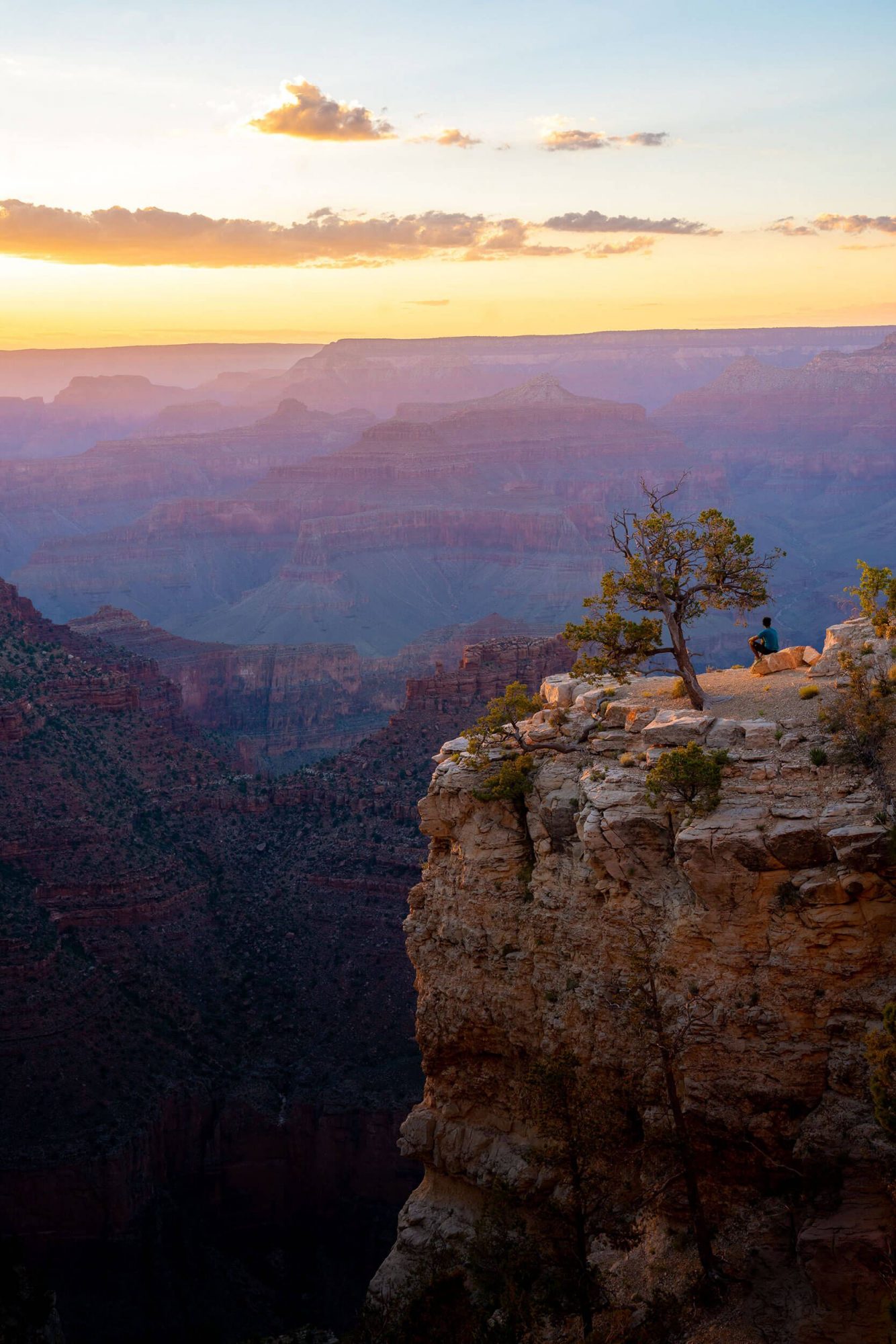 a man looks out into the grand canyon in arizona while on a cliff at sunset | photo by jake landon schwartz