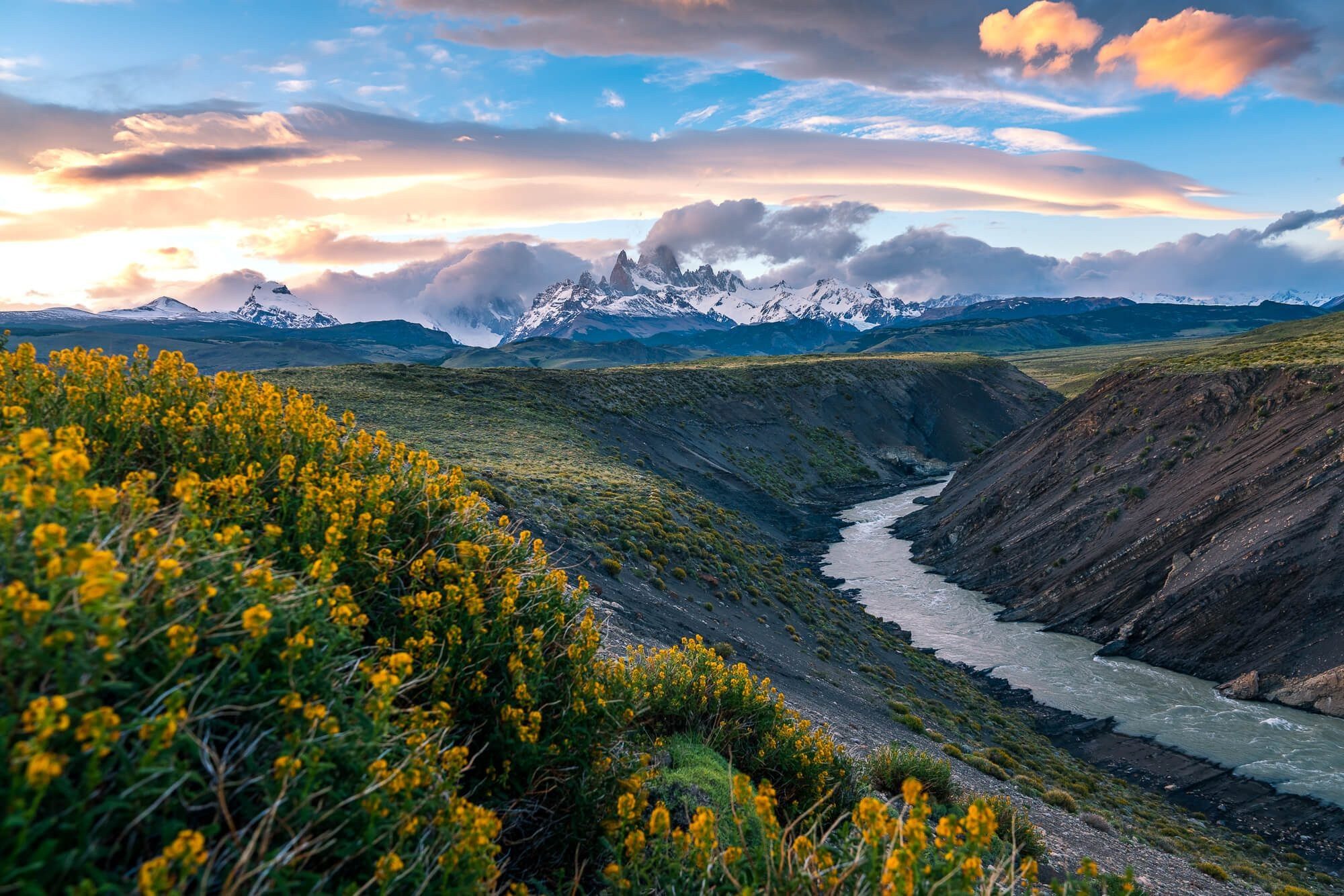 sunset over mount fitz roy in el chalten argentina patagonia with yellow flowers and the las vueltas river | photo by jake landon schwartz