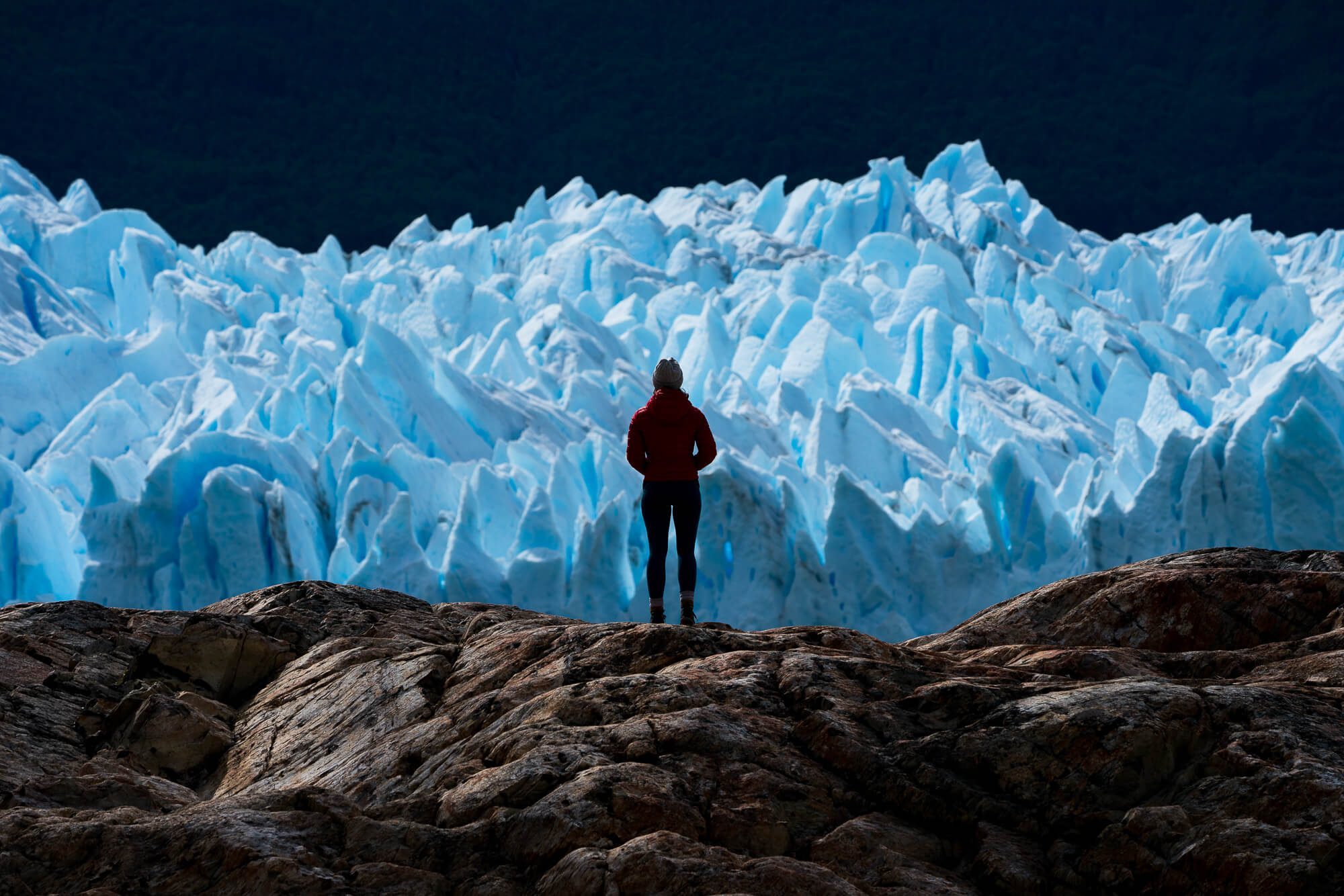 carly wallace stands and looks at perito moreno glacier in el calafate argentina in patagonia shot with sony a7rii and sony 100-400 gm lens | photo by jake landon schwartz